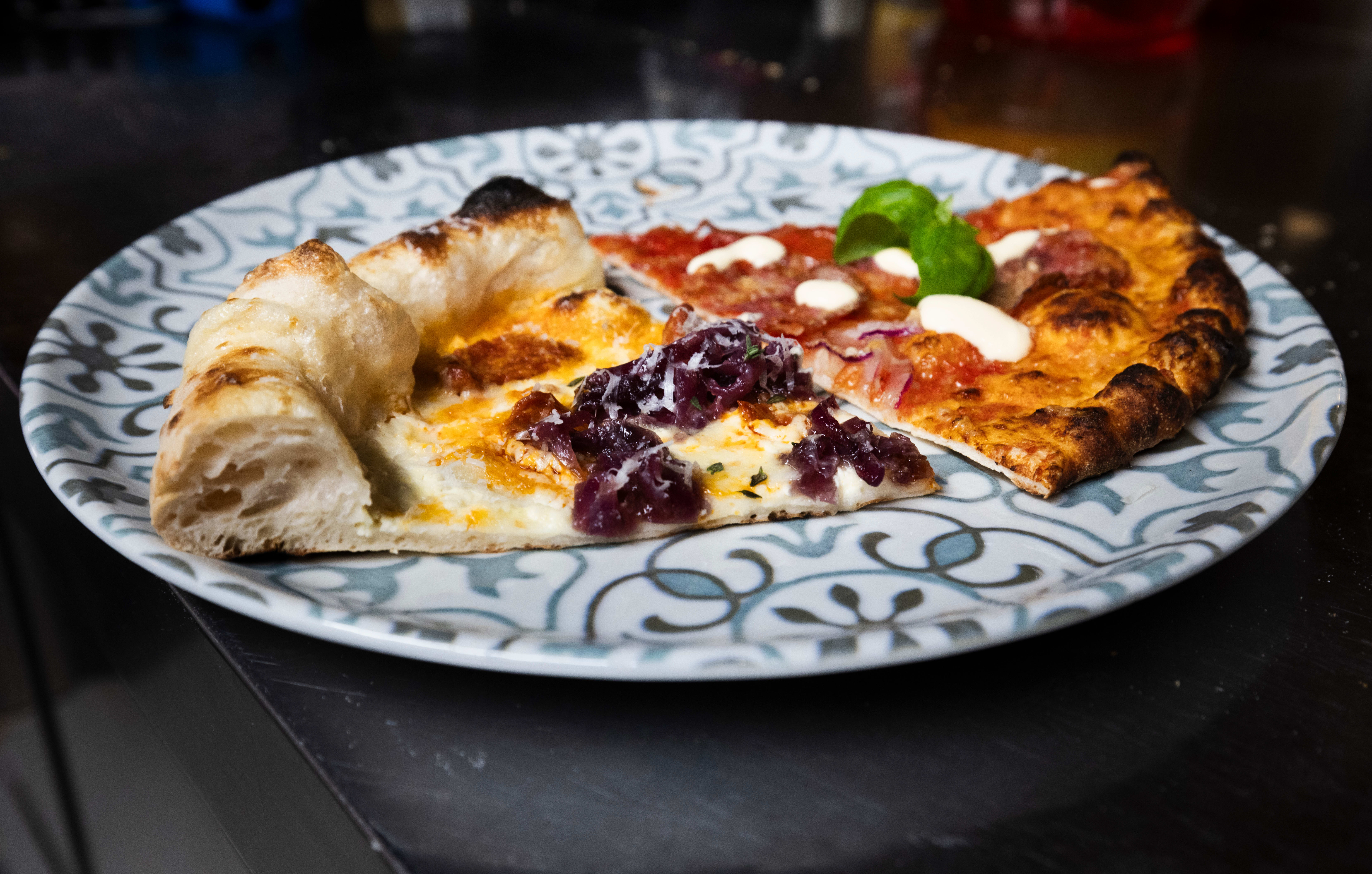 En napolitansk og romersk pizza side om side. De napolitanske er mykere og har høyere kant, mens den romerske er sprø og vanligvis nesten uten kant.