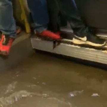 Her prøver busspassasjerene å holde seg tørre på bena