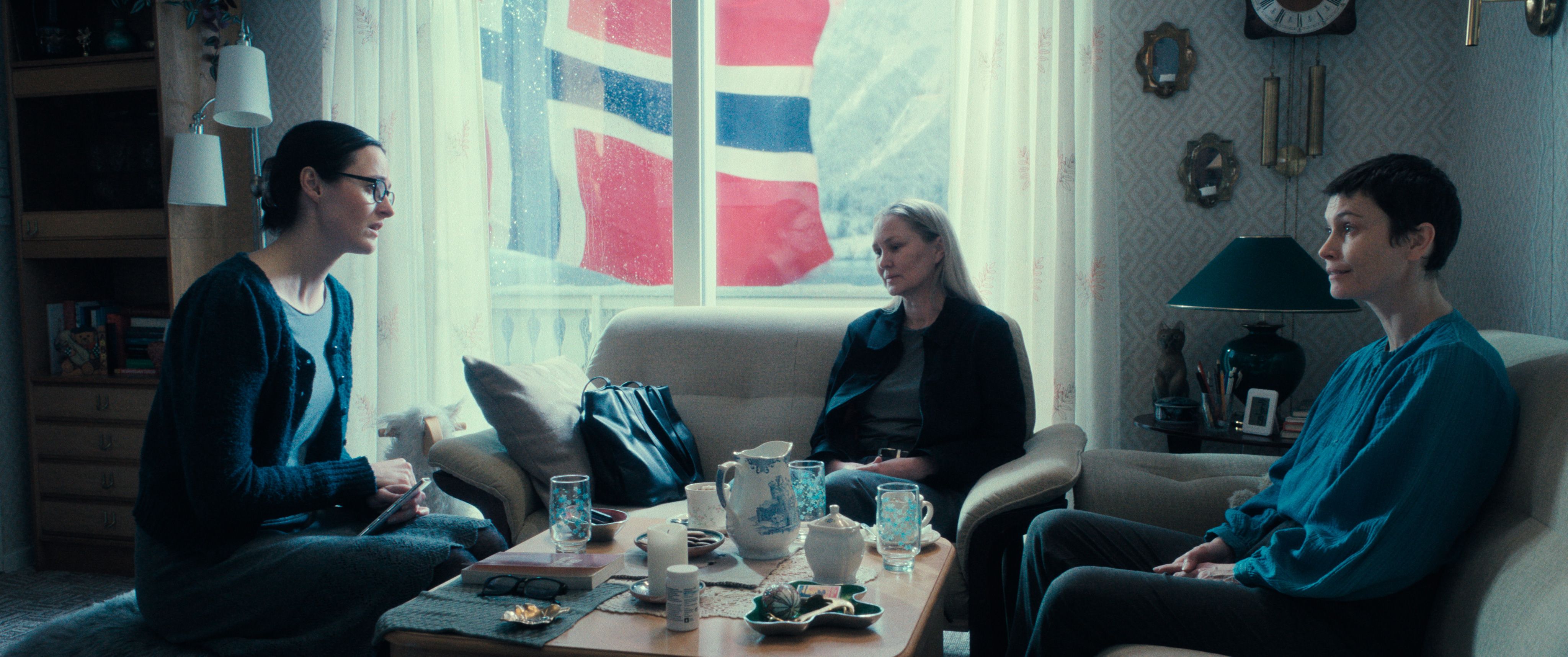 Det norske flagget vises hyppig i «Fjord».  Fembarnsmoren Lisbet (Renate Reinve) har fått besøk av Gunda fra barnevernet (Ellen Dorrit Petersen) og lærer Frida (Lisa Loven Kongsli).