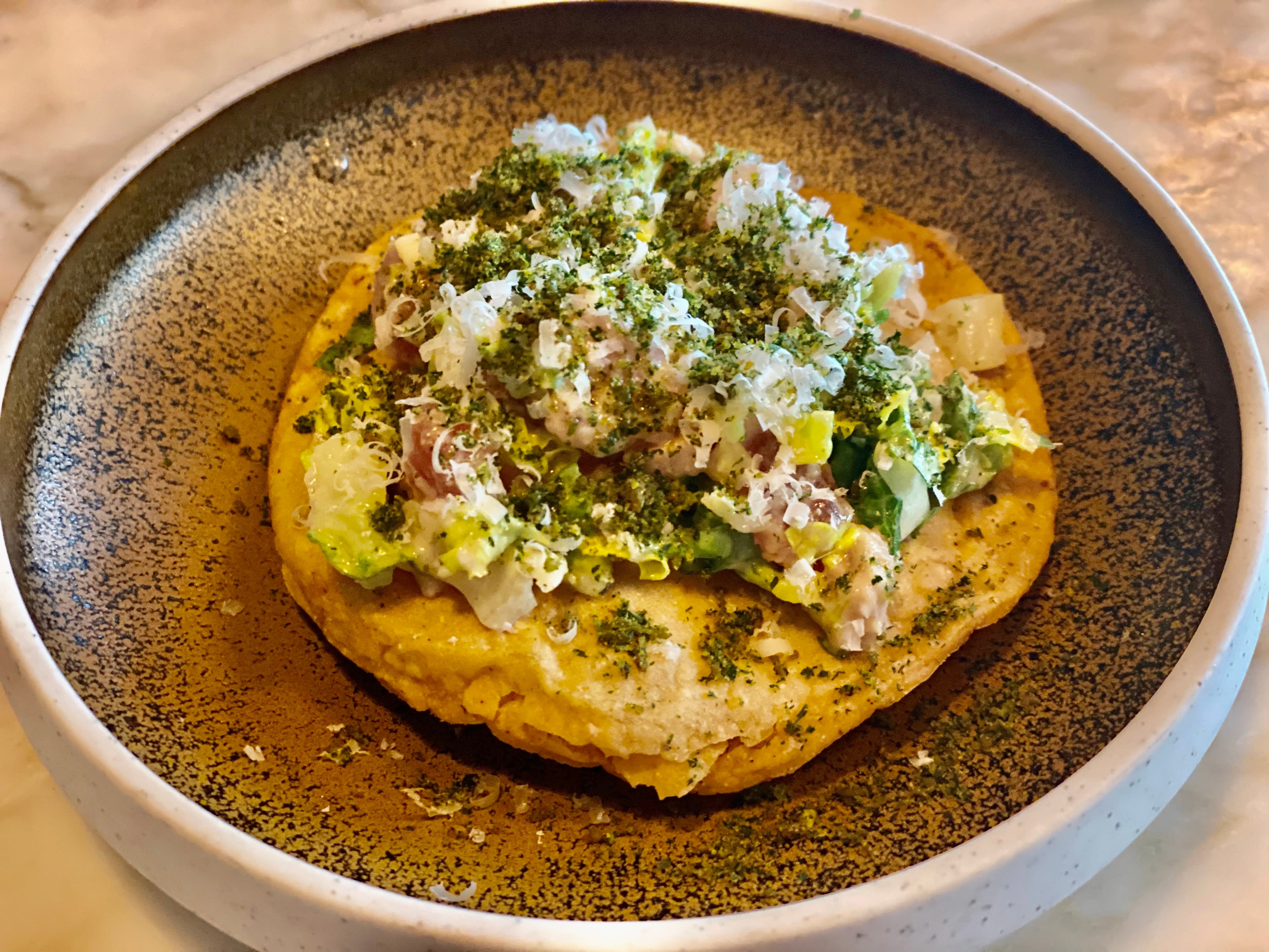 Sprø tostada med tunfisk, parmesan, hjertesalat og ansjosbasert dressing. 