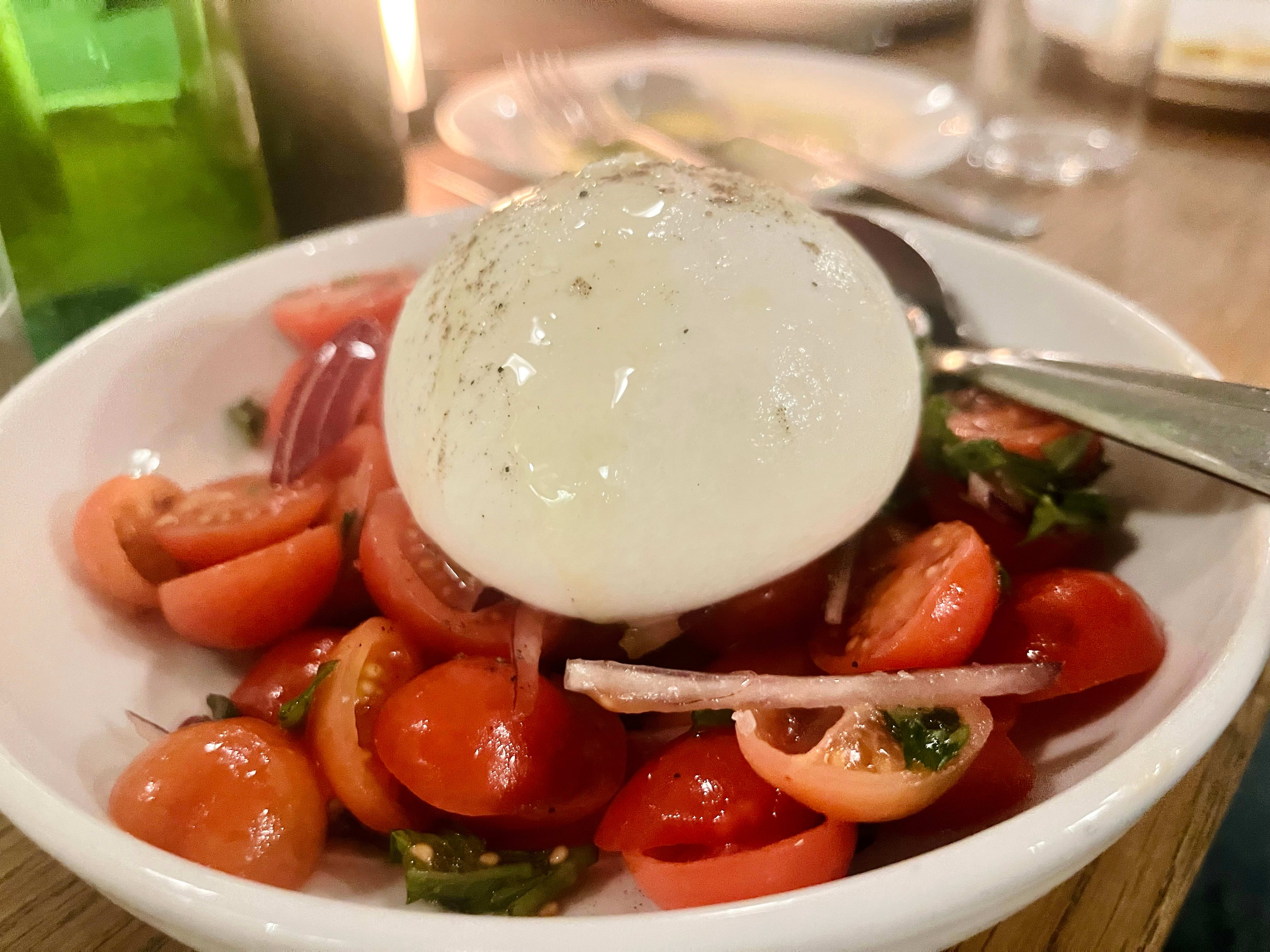 Capresesalaten kan enten bestilles med mozzarella eller den overdådige storesøsteren burrata, som er fylt med fløte og stracciatella. Digg!