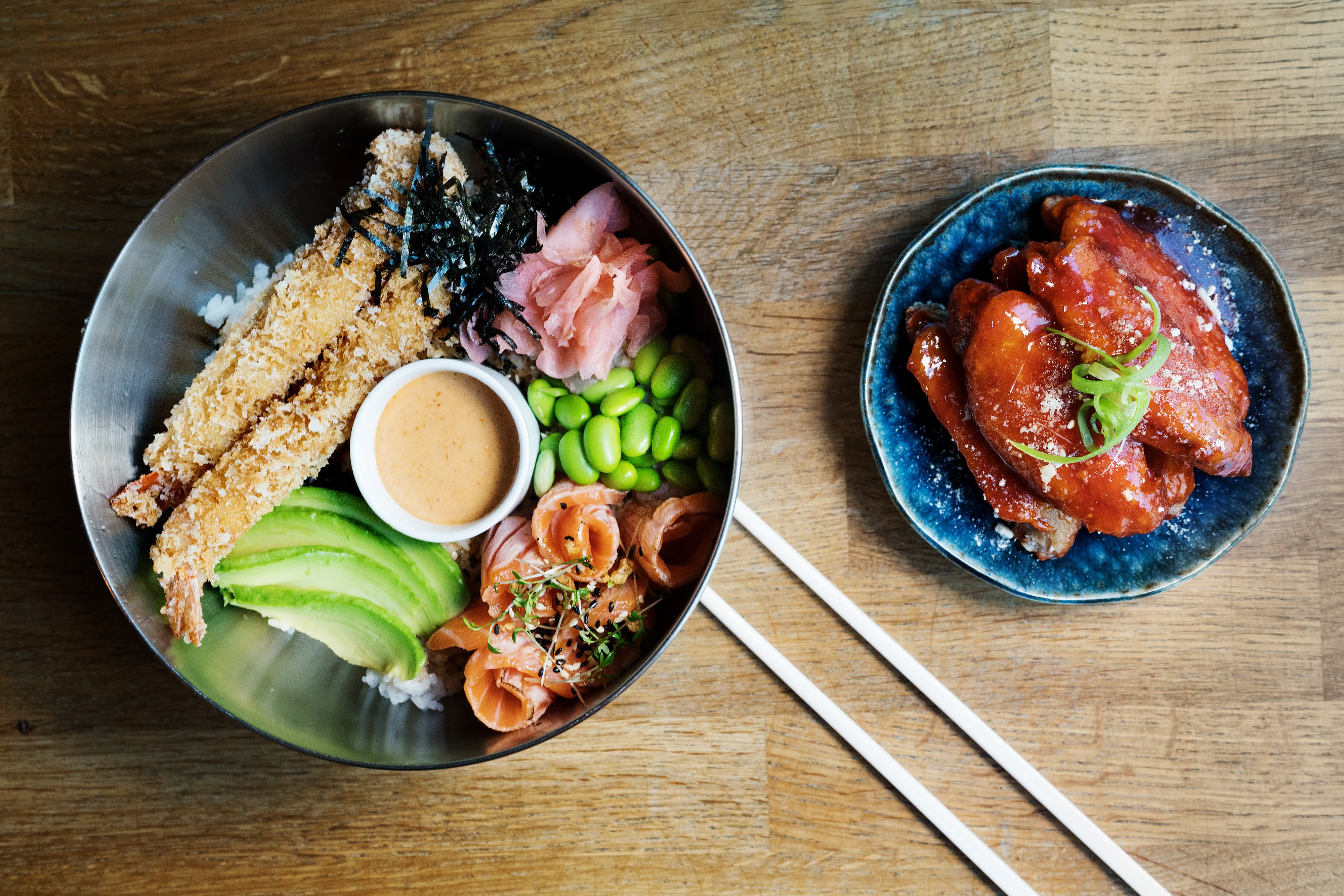 Koreanske kyllingvinger og fire bowl med laks og tempurascampi. 