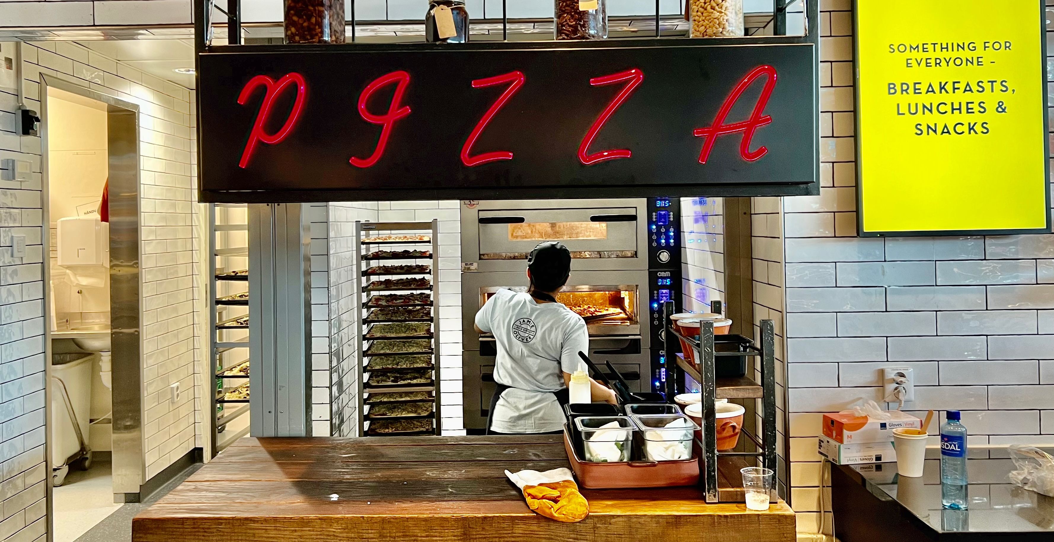 Her står mange brett med pizza klare. 