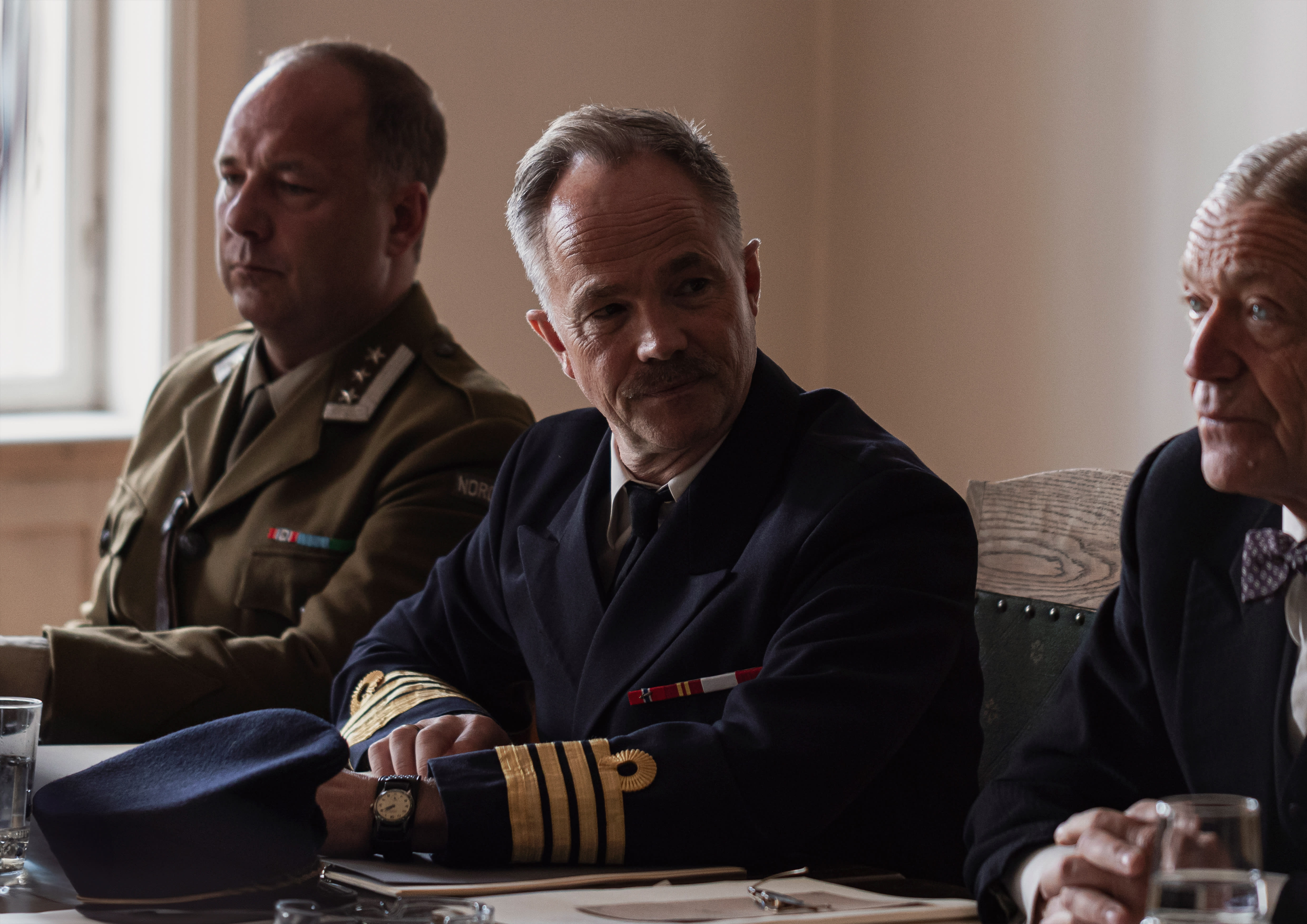 Rammefortellingen foregår i 1946. Da ble oberst Eriksen innkalt til høring av en militærkommisjon. Skuespiller Jon Øigarden (i midten) og Terje Strømdahl (t.h.) 