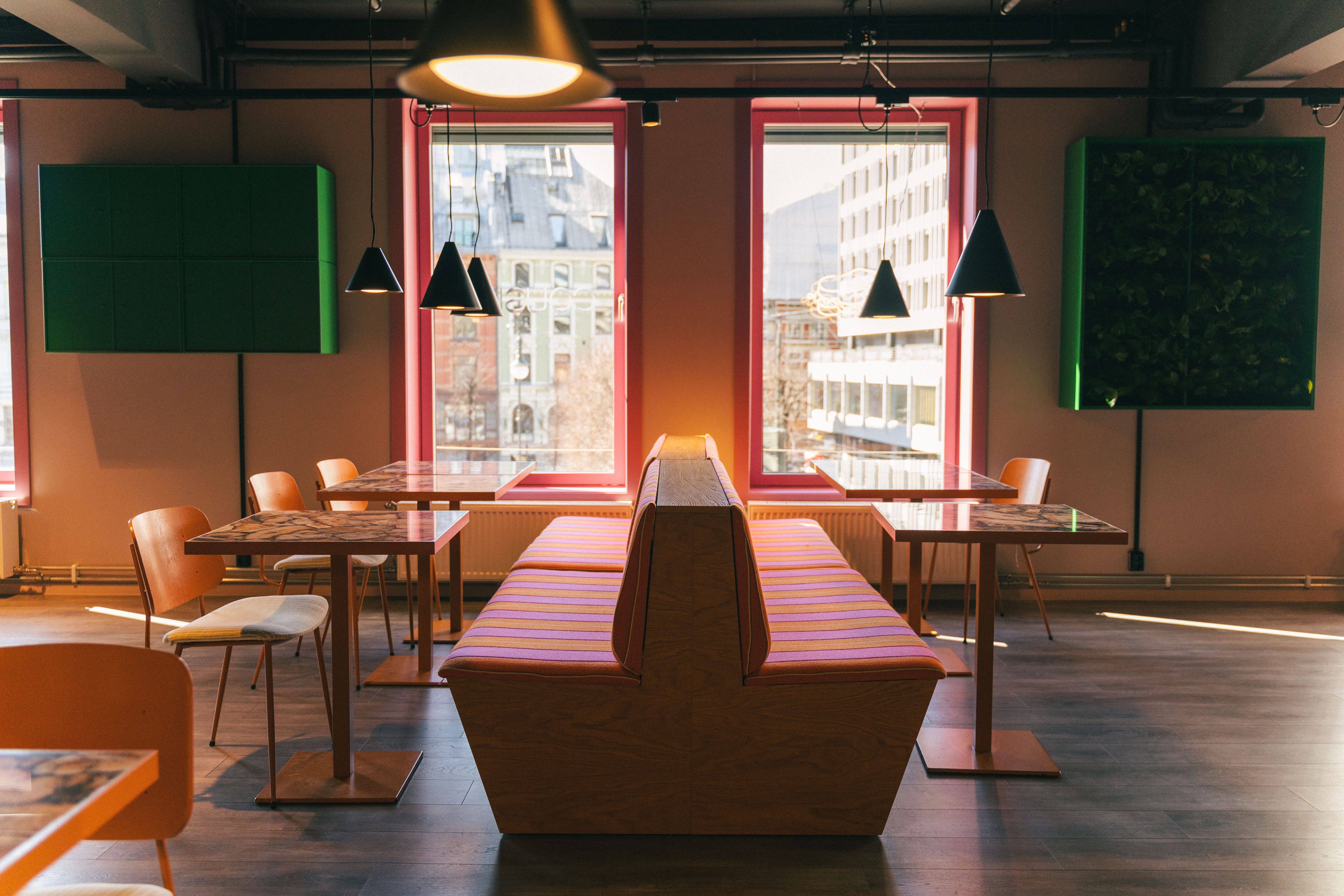 Cousins er innredet med grønne planter som står i kontrast til det rosa og oransje interiøret.