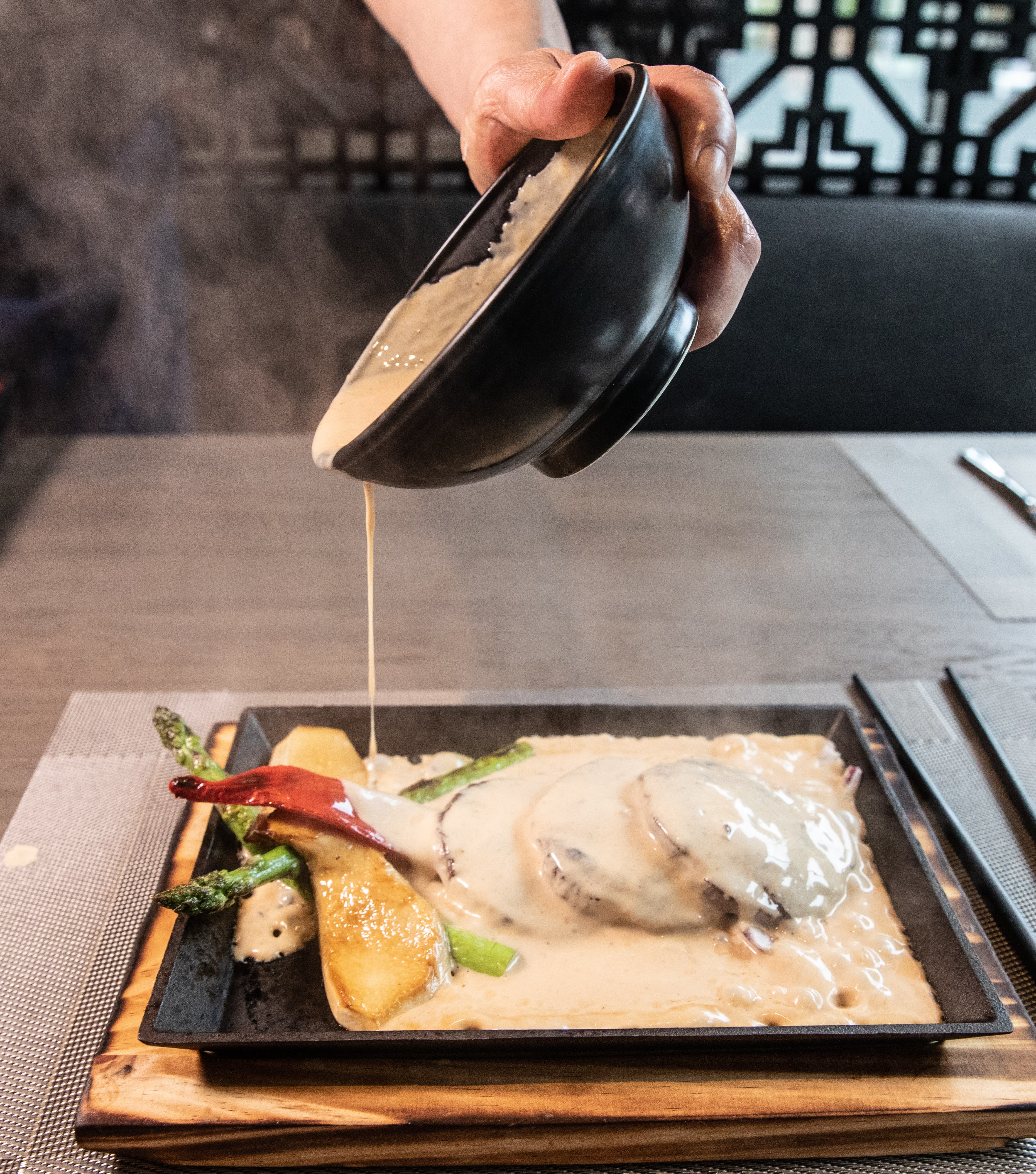 Varm saus helles over medaljongene på fresende varm støpejernsplate.