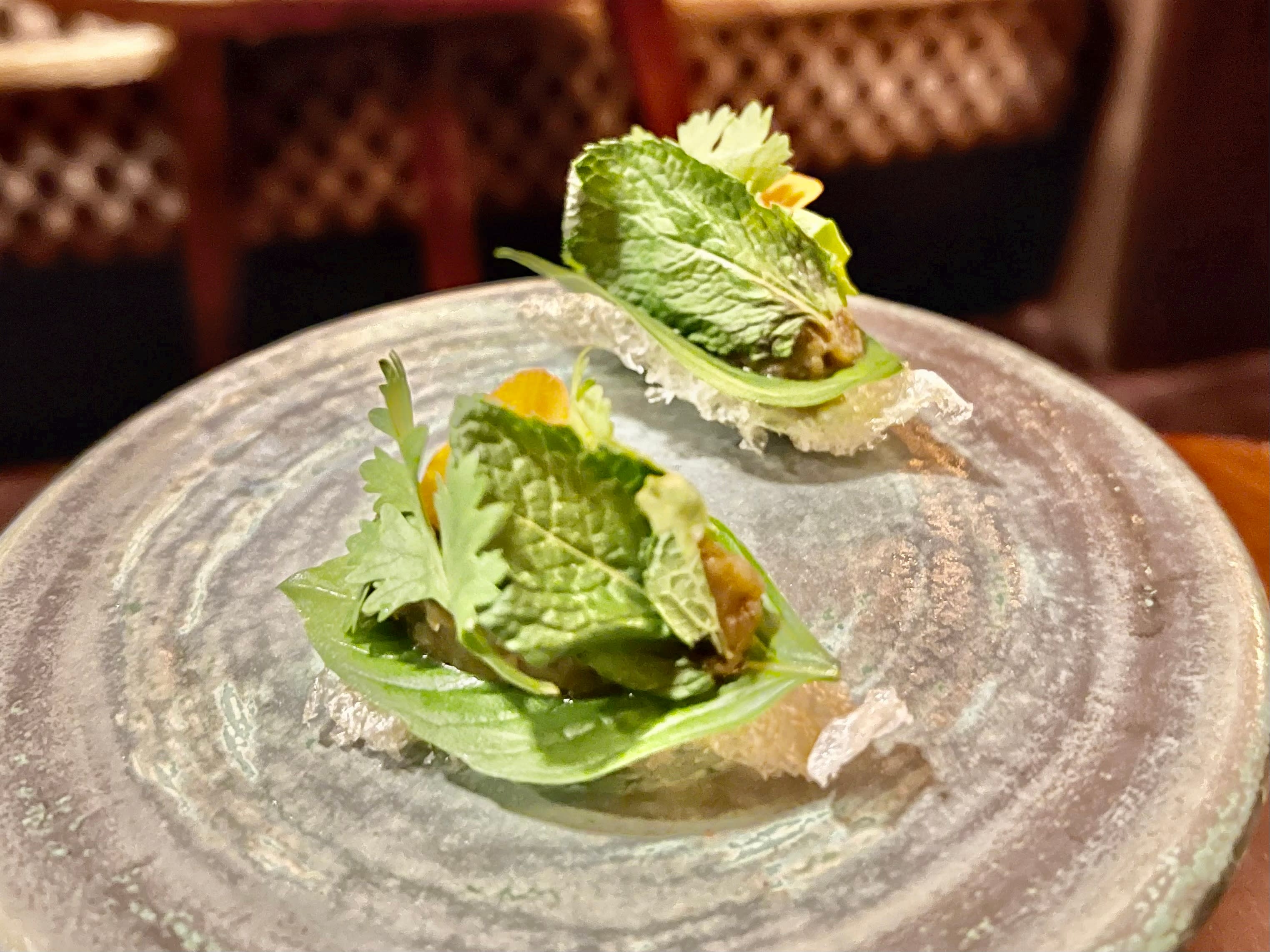 Nahm prik laget på bakt aubergine med chili, sprø svinesvor, thai basilikum, koriander og mynte.