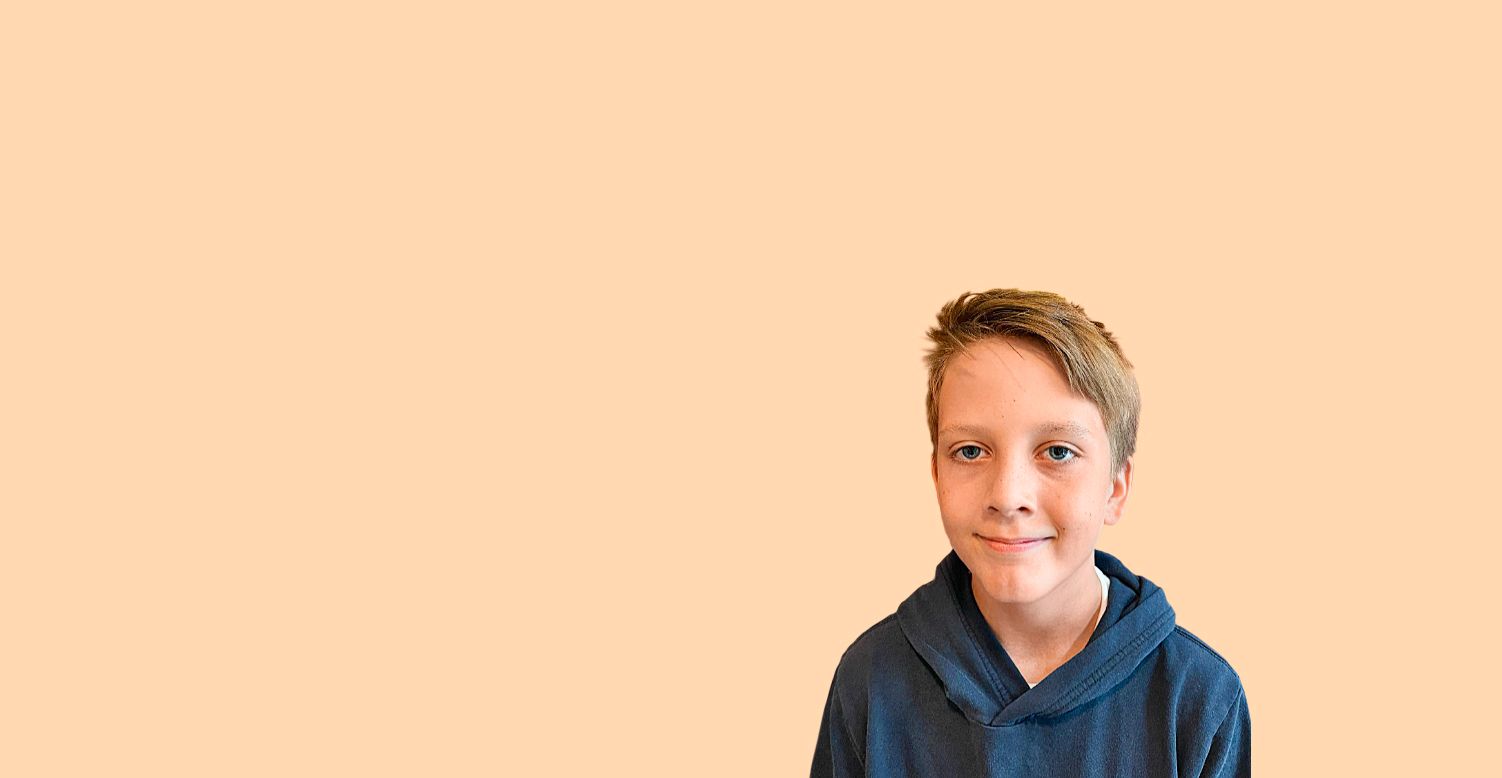 En gutt med sideveis og mørkeblå hettegenser smiler litt fra en redigert, lys oransje bakgrunn.