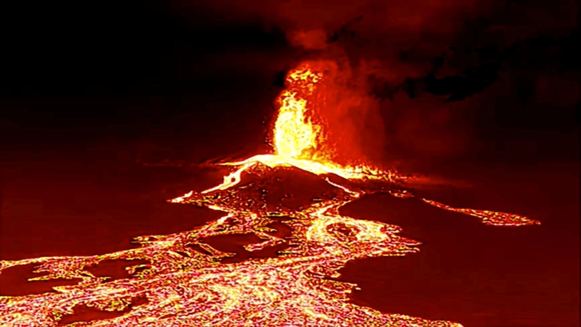 Lava tyter ut av en vulkan og renner nedover.