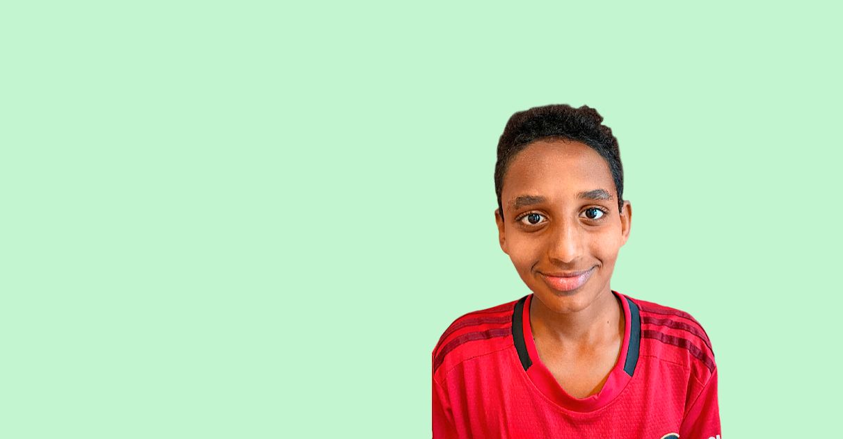 En gutt med kort, svart hår og rød sports-T-skjorte smiler fra en redigert, pastellgrønn bakgrunn. 