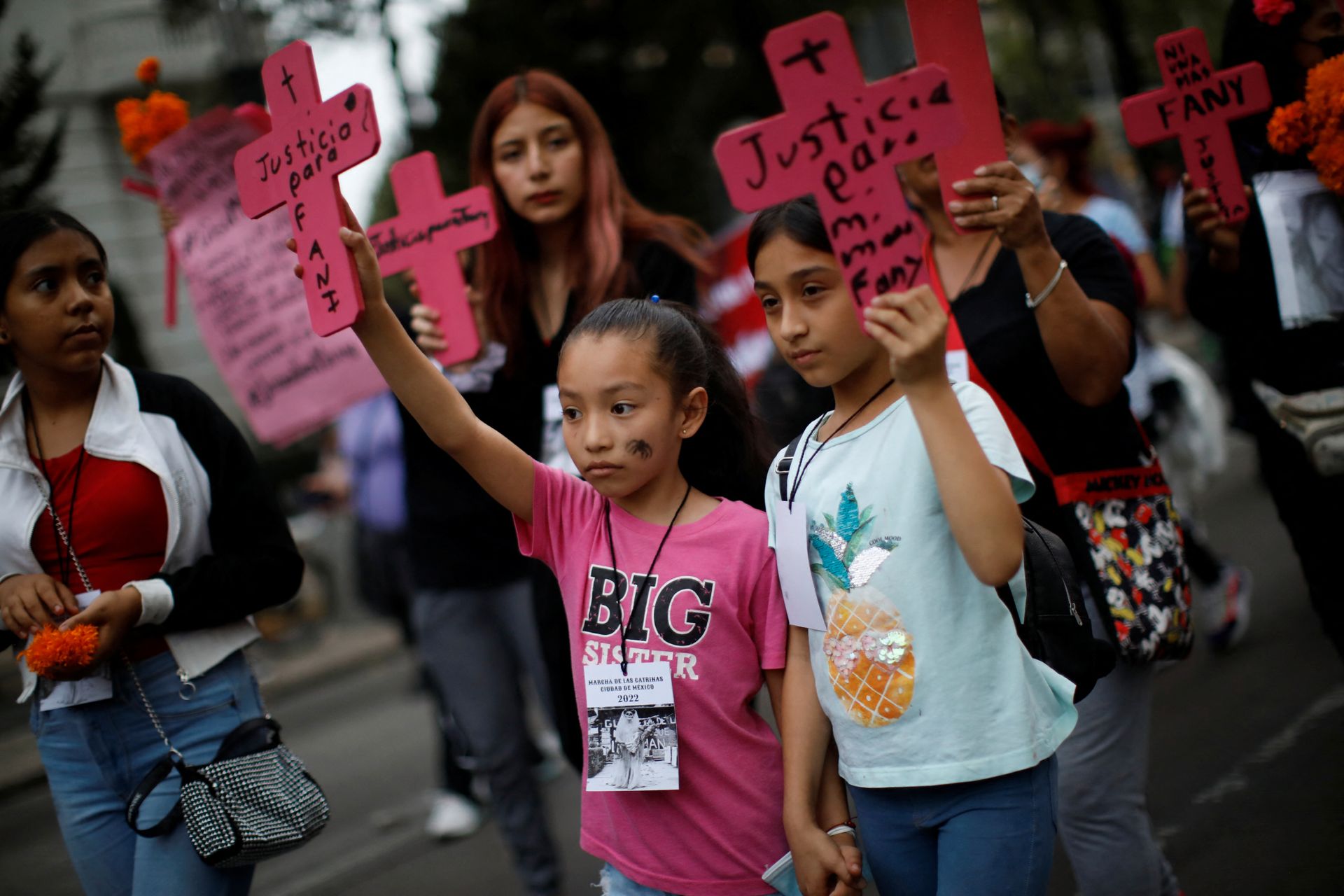 To unge jenter deltar på en demonstrasjon med rosa plakater.