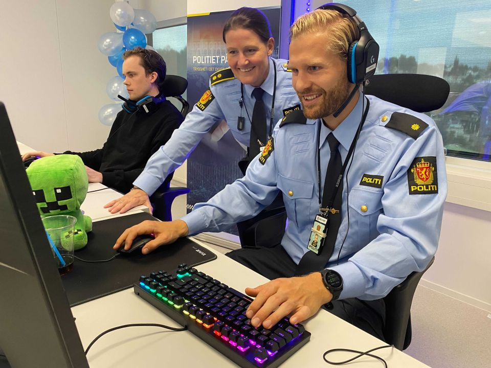 To menn og en kvinne i lyseblå politiuniformer sitter foran PC-skjermer og trykker på tastaturene.