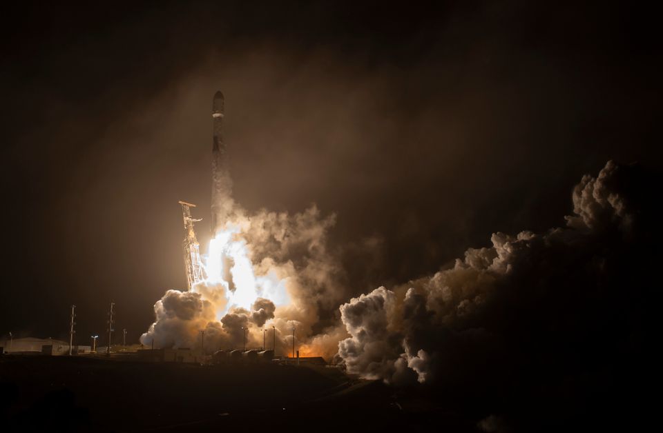 En rakett skytes opp fra bakken, mot en mørk himmel, mens masse røyk fyller området.