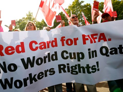 Mange mennesker med flagg protesterer ute, med en stor plakat som det står "Rødt kort til Fifa" på.