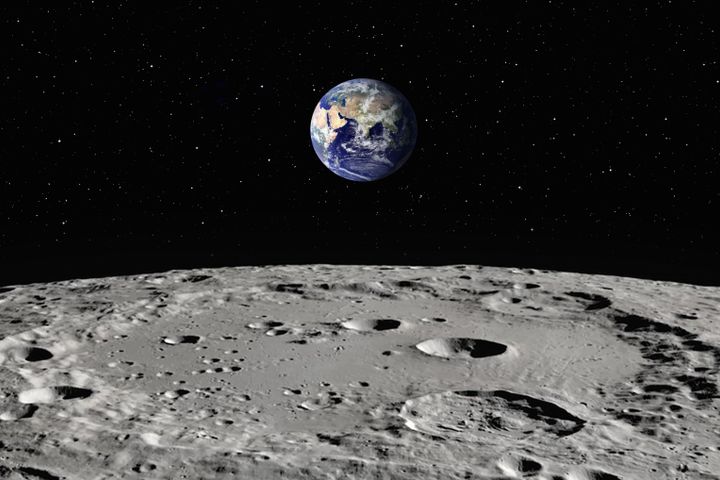 Et bilde av den gråaktige bakken på månen, som det er små groper i, og i bakgrunnen ser man jorden langt avgårde.