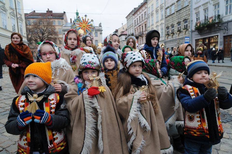 Mange barn med varme klær og luer går i en gate.