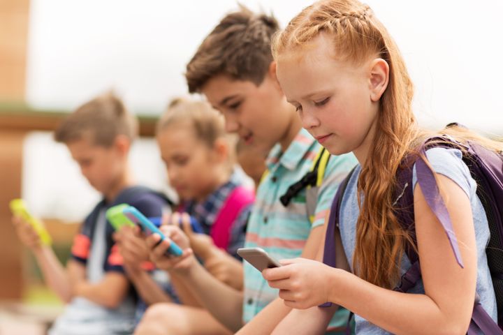 En gruppe med barn står og ser på hver sin mobiltelefon.