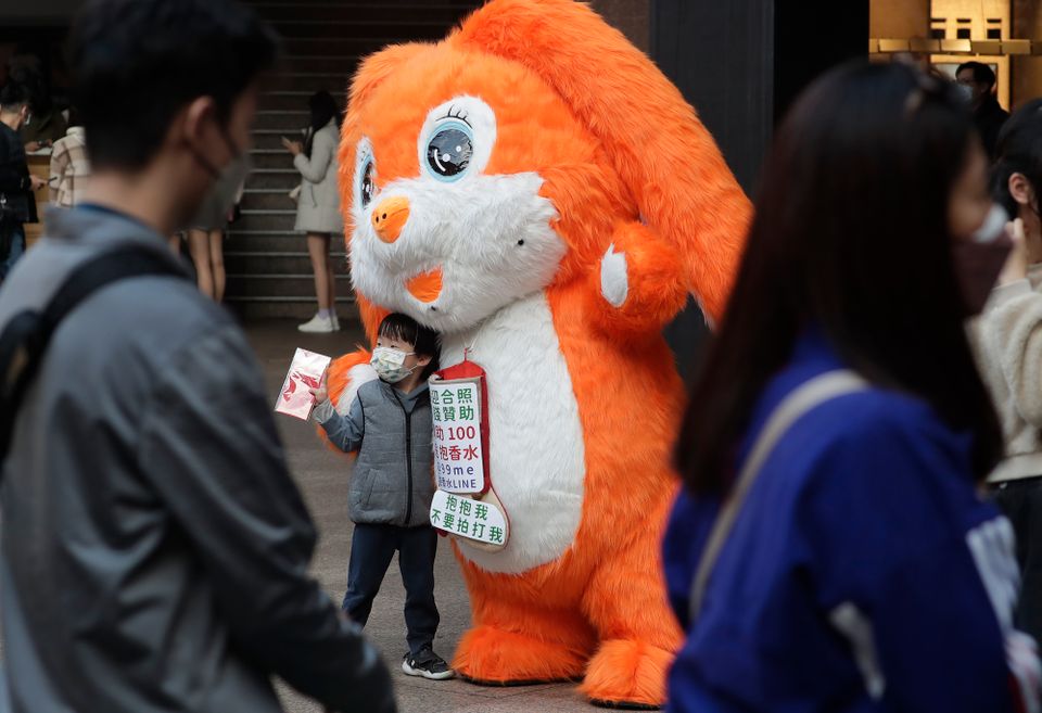En liten gutt poserer på gaten sammen med en person i en stor, oransje kanindrakt.