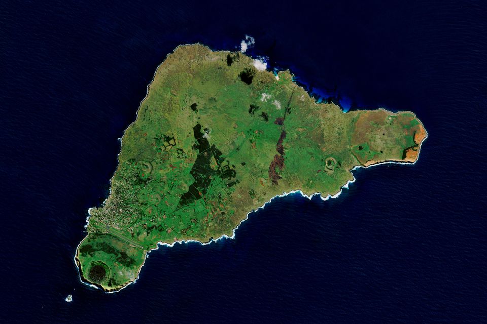 En satellitt-bilde viser en enslig øy formet som en ujevn trekant, som er dekket av et grønt landskap.