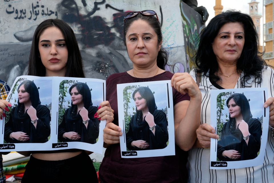 Tre kvinner holder opp plakater med bilde av en ung kvinne på.