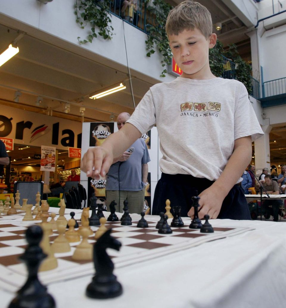 En ung og konsentrert gutt gjør et trekk på et sjakkbrett.