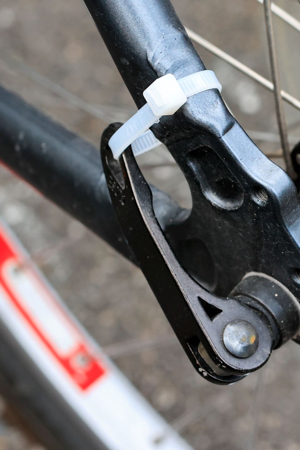 Nærbilde av den sorte klaffen på sykkelhjulet, som man bruker til å løsne hjulet, festet til ramma med en hvit strips.