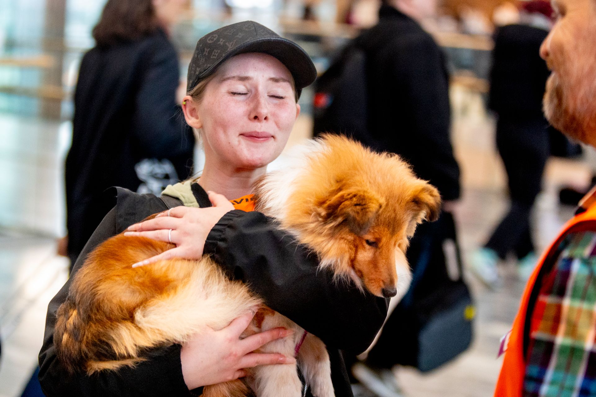 En hund som ligger i armene på en dame med caps som ser ut til å gråte av glede