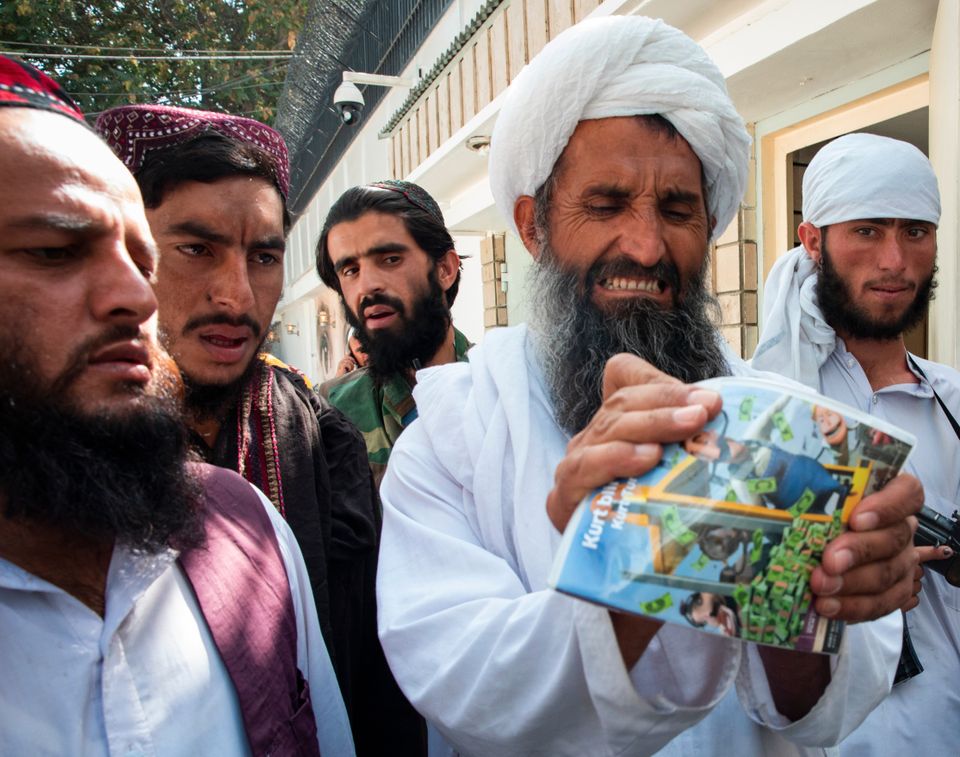 En skjeggete mann med turban forsøker å knekke en DVD mens flere andre ser på.