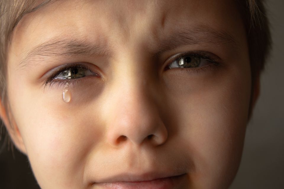 Nærbilde av et ungt guttangikt med tårer rennende nedover kinnene. 