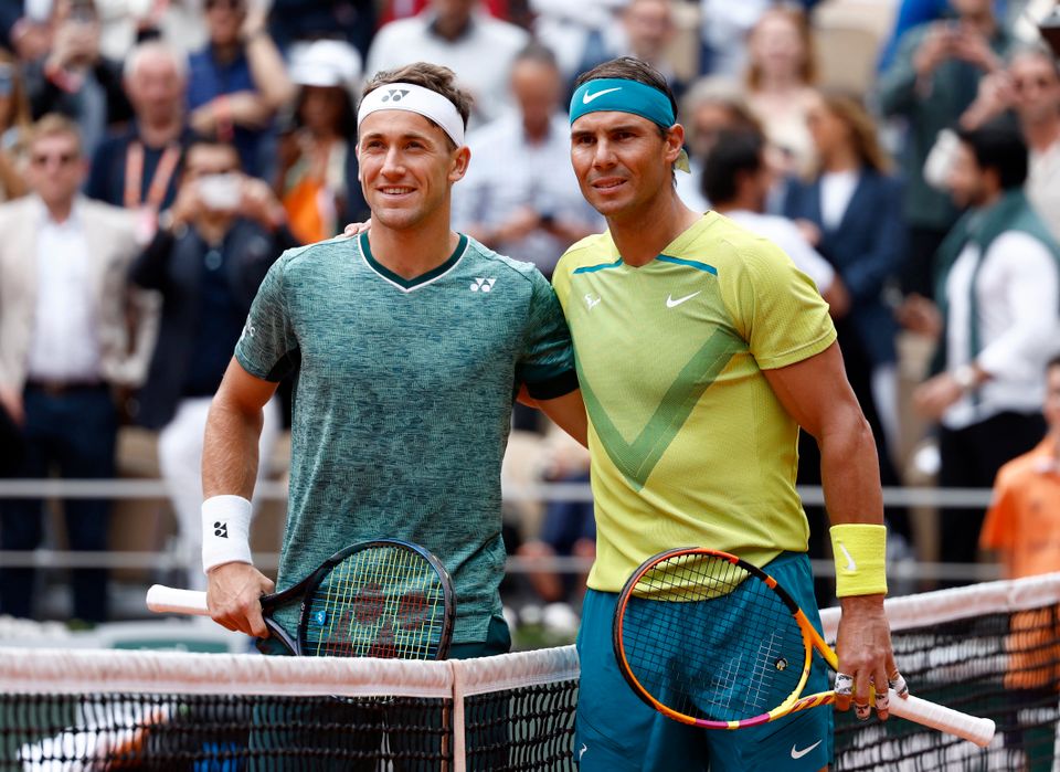 To menn står ved et tennisnett og holder rundt hverandre - begge har på svettebånd.