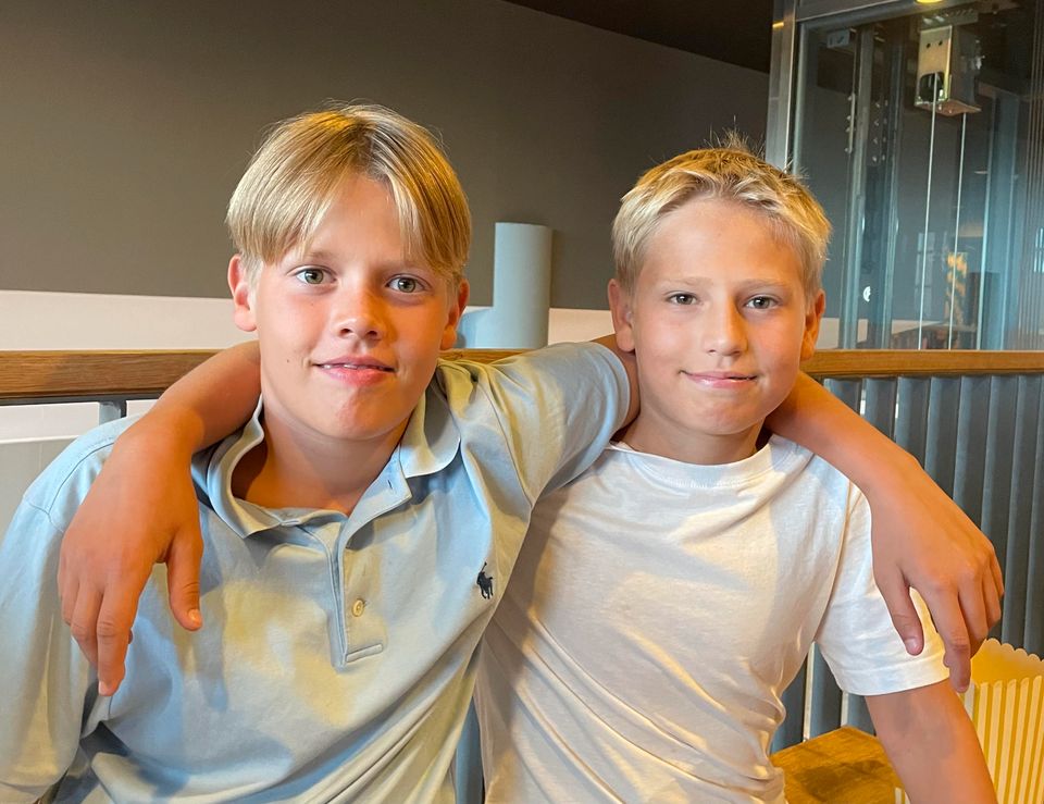 Bilde av to gutter med blondt hår som holder rundt hverandre og ser inn i kamera.