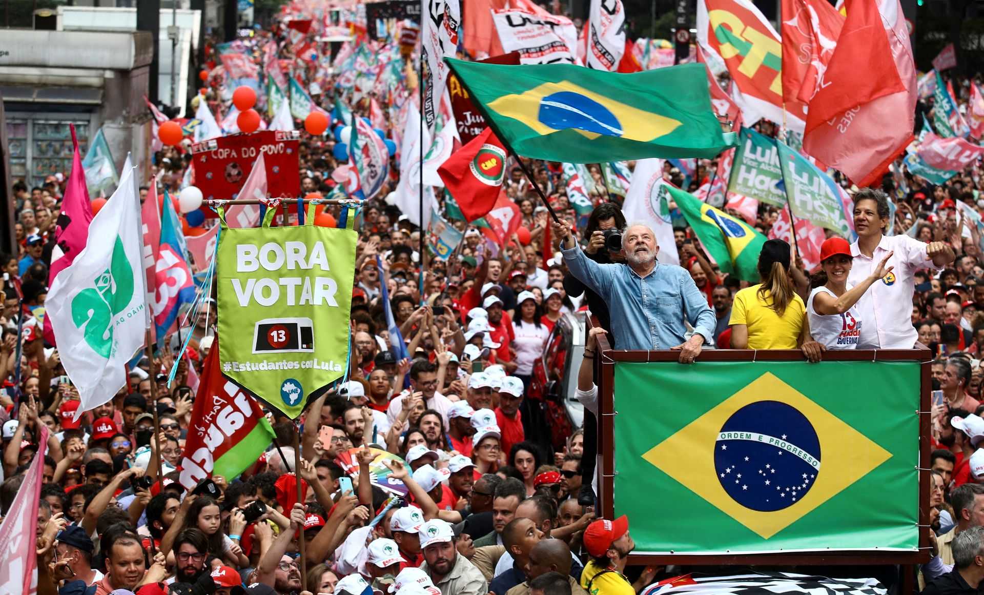 Lula veiver med det brasilianske flagget i en parade sammen med mange mennesker