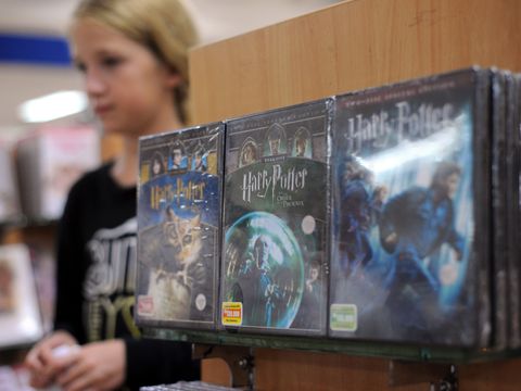 Tre Harry Potter-DVD-er utstilt i en butikk, mens en jente går forbi i bakgrunnen