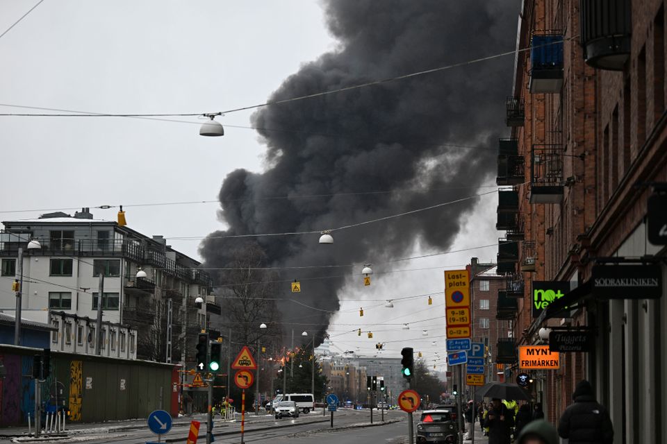 Bilde av en gate og i bakgrunnen er det flammer og veldig mye røyk.