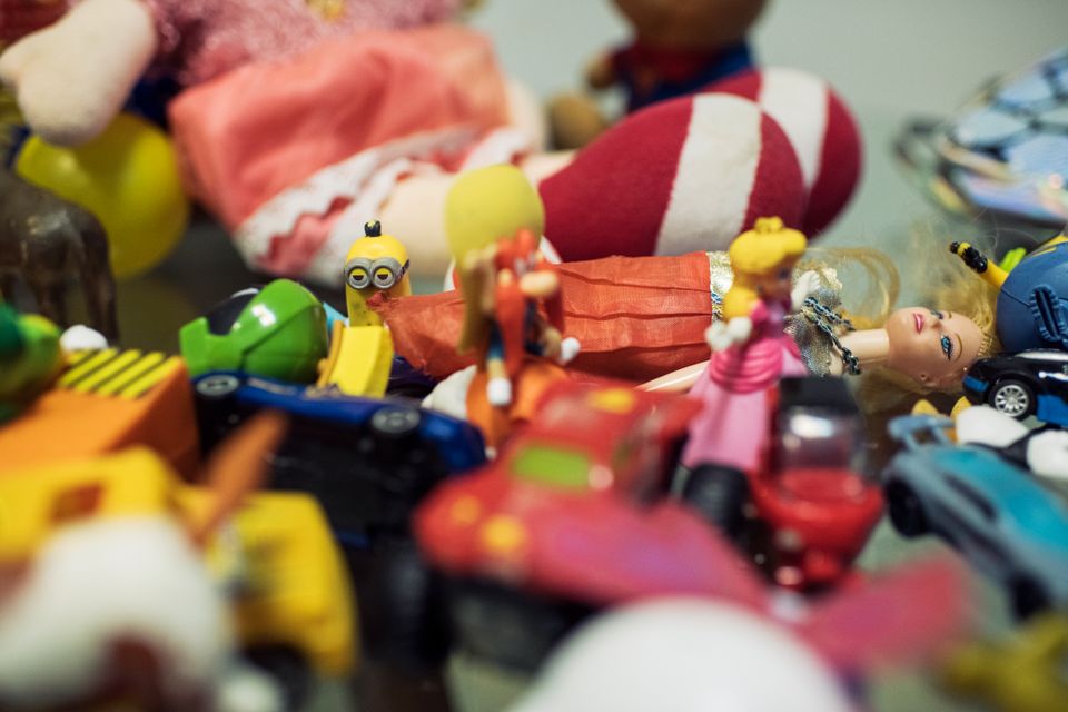 Leker i ulike farger ligger oppå hverandre på et bord, blant andre en Barbie og en gul minion