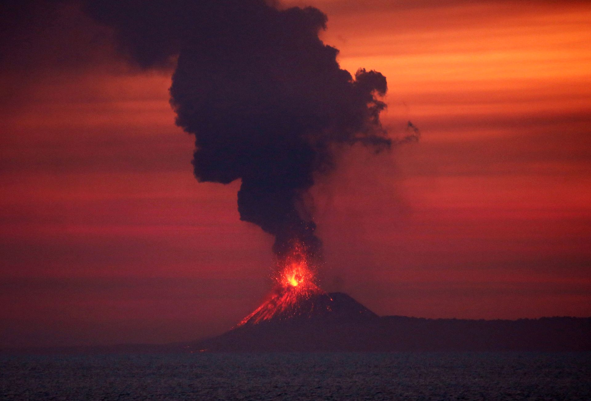 Flammer og mye røyk tyter ut av en vulkan.