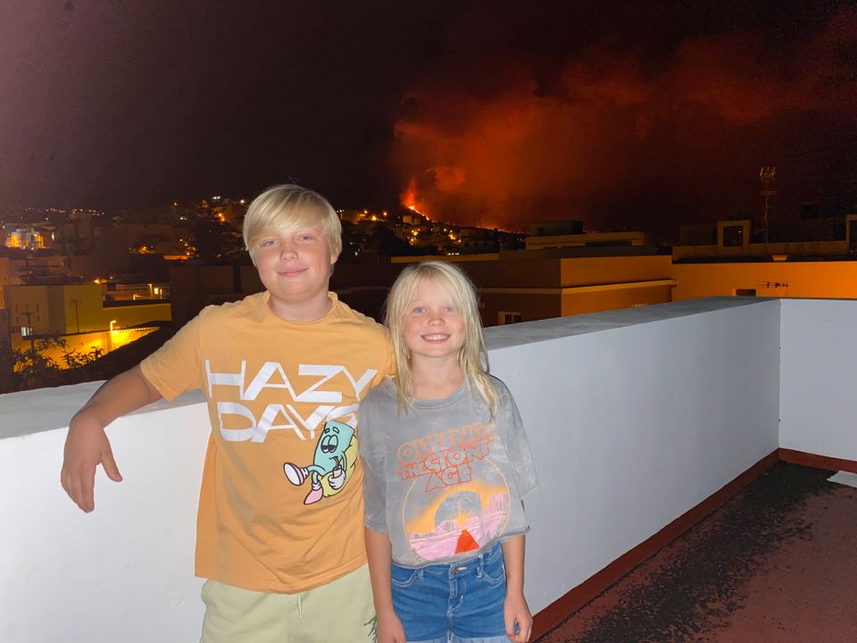 Aaron og Filippa står på verandaen. I bakgrunnen kan man se vulkanen.