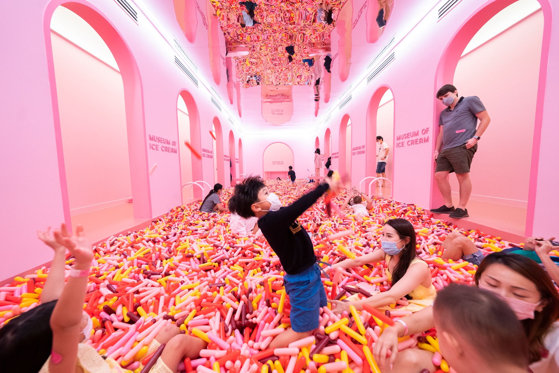 Barn leker i et knallrosa type ballrom hvor gulvet er fylt med objekter som likner fargerikt tuttifrutti-strøssel.