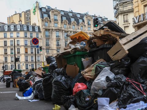En gate med typisk parisiske murbygninger har en enorm haug med søppel midt i veien.