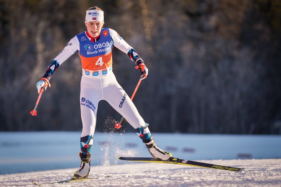 En skiløper går i sporet med hvit drakt og hvit lue og med rødt startnummer. 
