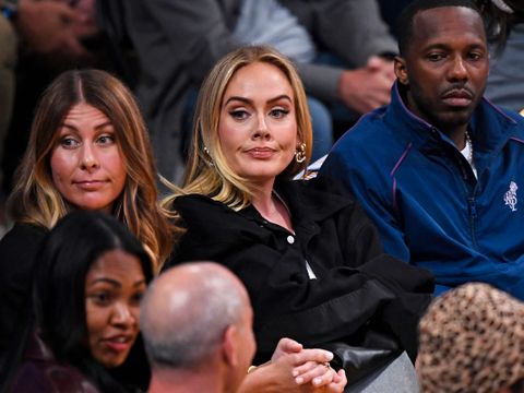 Adele, en kvinne i 30-årene med lyst hår, sitter mellom andre personer på en av de første radene på en basketball-kamp.