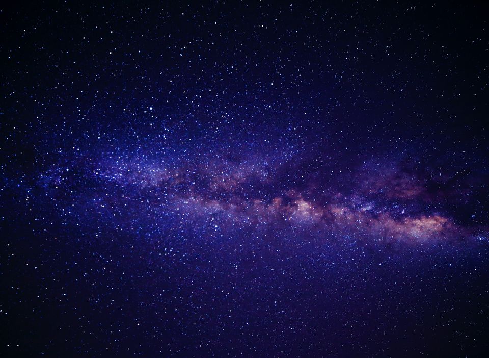 Et lilla belte farger skinner på en mørkeblå stjernehimmel som er vårt solsystem: Melkeveien.
