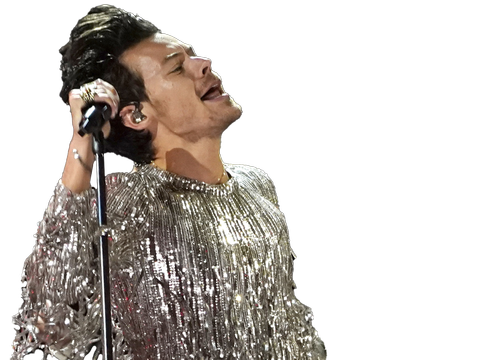 Harry Styles, en mann i tidlig 30-år med en glitrende søvdrakt med masse rysjer på, står og holder en mikrofon.