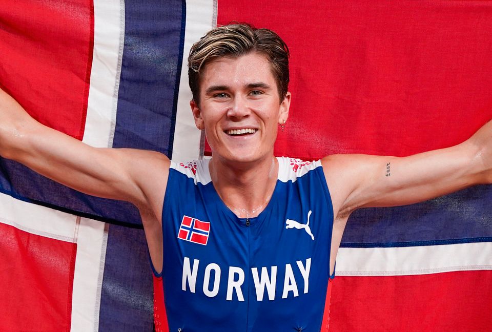Jakob Ingebrigtsen løfter et norsk flagg og feirer OL-gull.