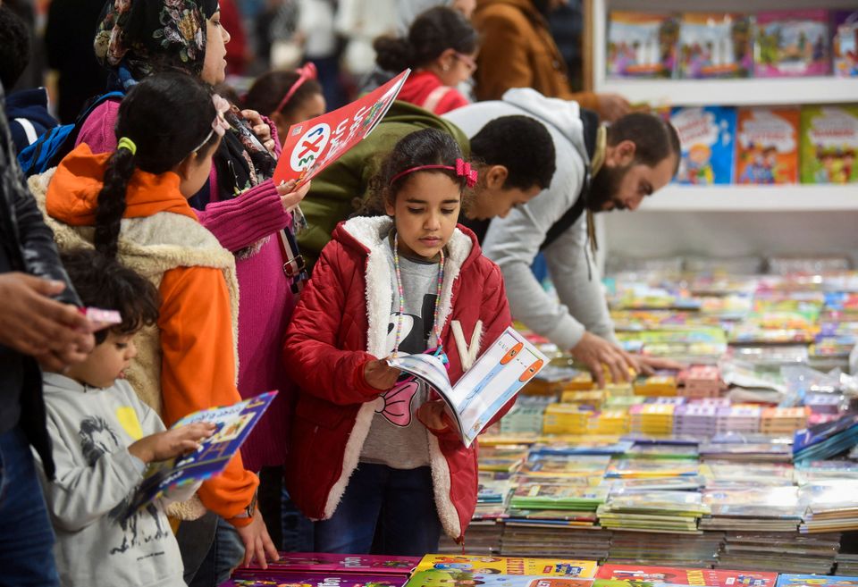 Et barn er på et marked med mange bøker og leser i en bok.