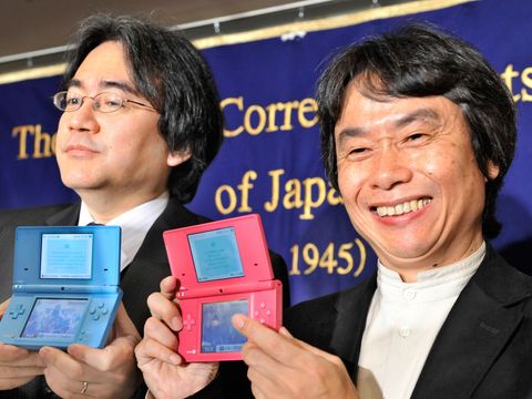 To japanske utvikle holder opp spillkonsoll og smiler