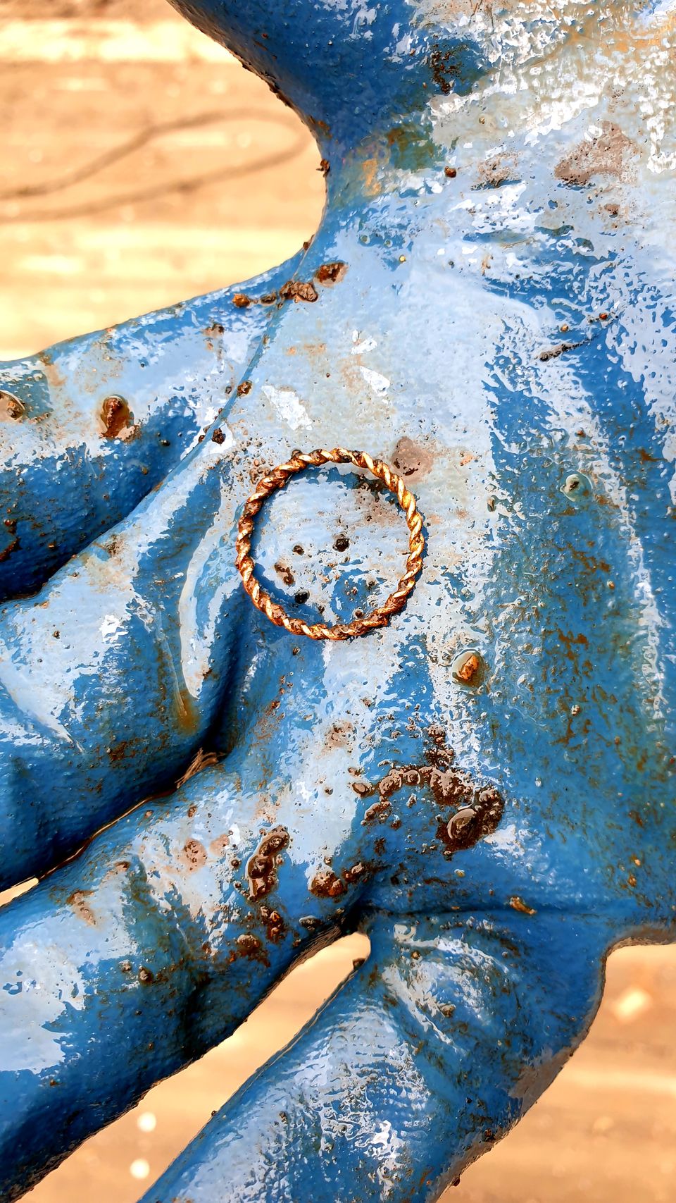 En blå hanske med litt gjørme på som holder en liten gullring.