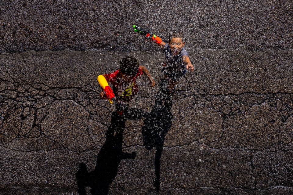To barn står på asfalten mens det drypper vann over dem.