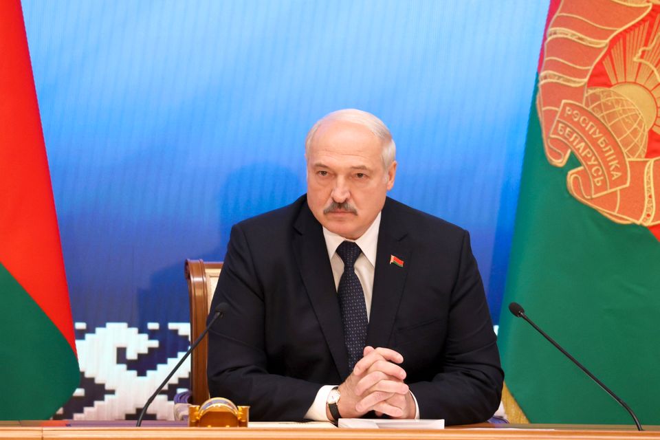 Portrettbilde av president Aleksandr Lukasjenko. Han folder hendene og ser morsk ut.