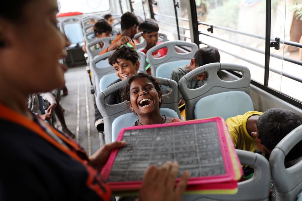 En gutt skrattler mens han snakker med læreren sin inne i en buss. 
